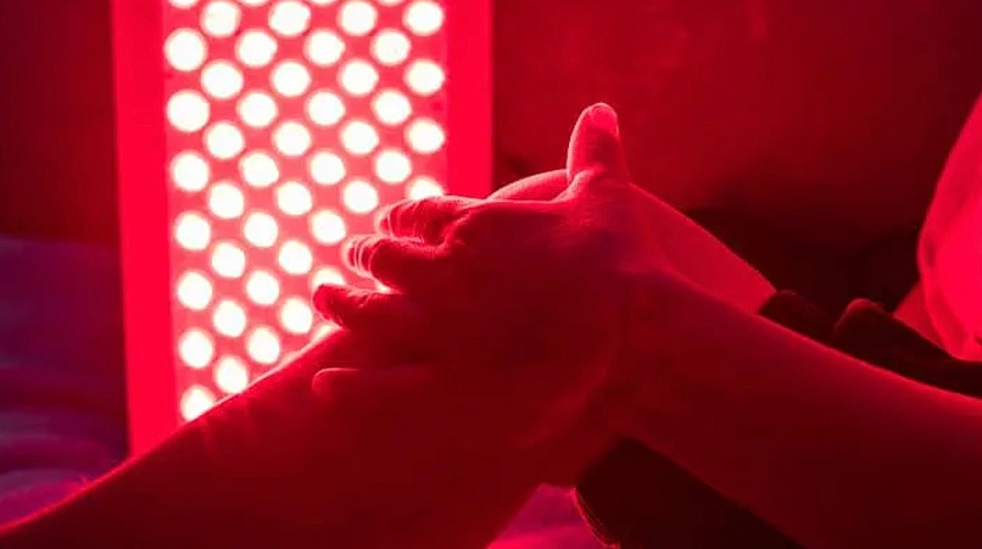 Hands under red light therapy treatment.