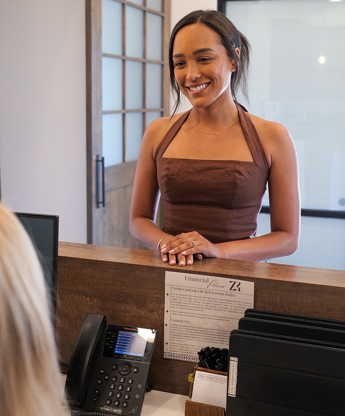 Smiling woman at reception desk greeting a client.