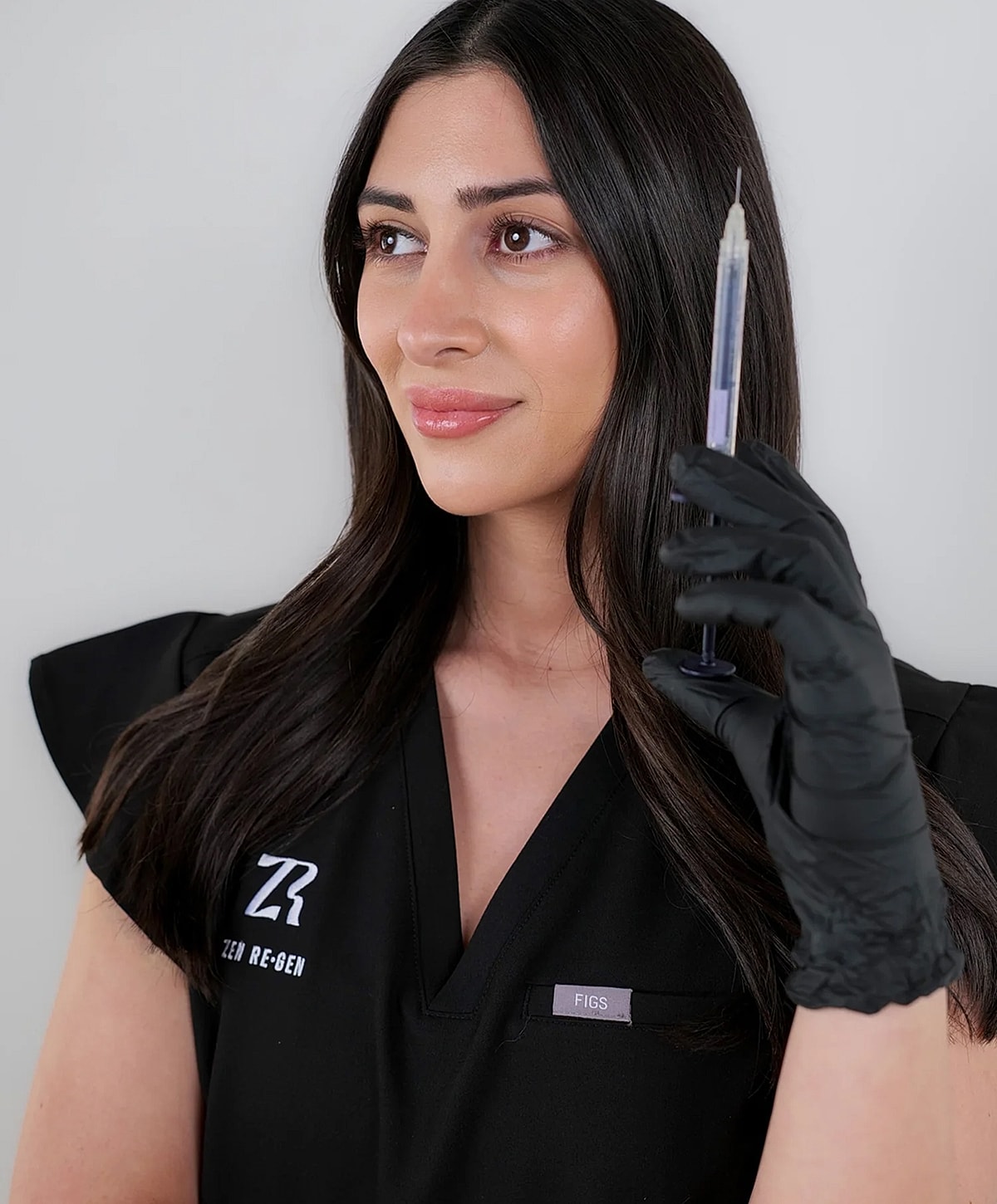 Woman holding a syringe in medical attire.