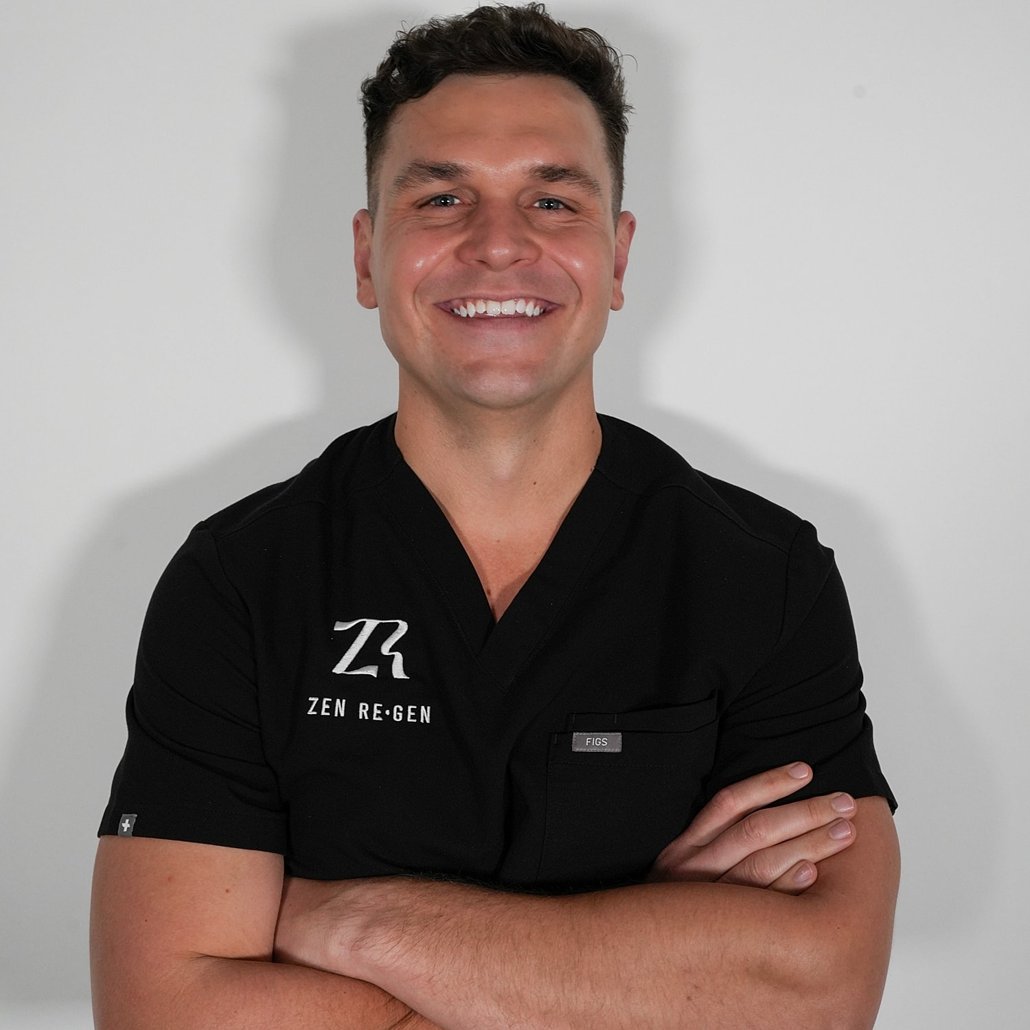 Smiling man in black medical scrubs.