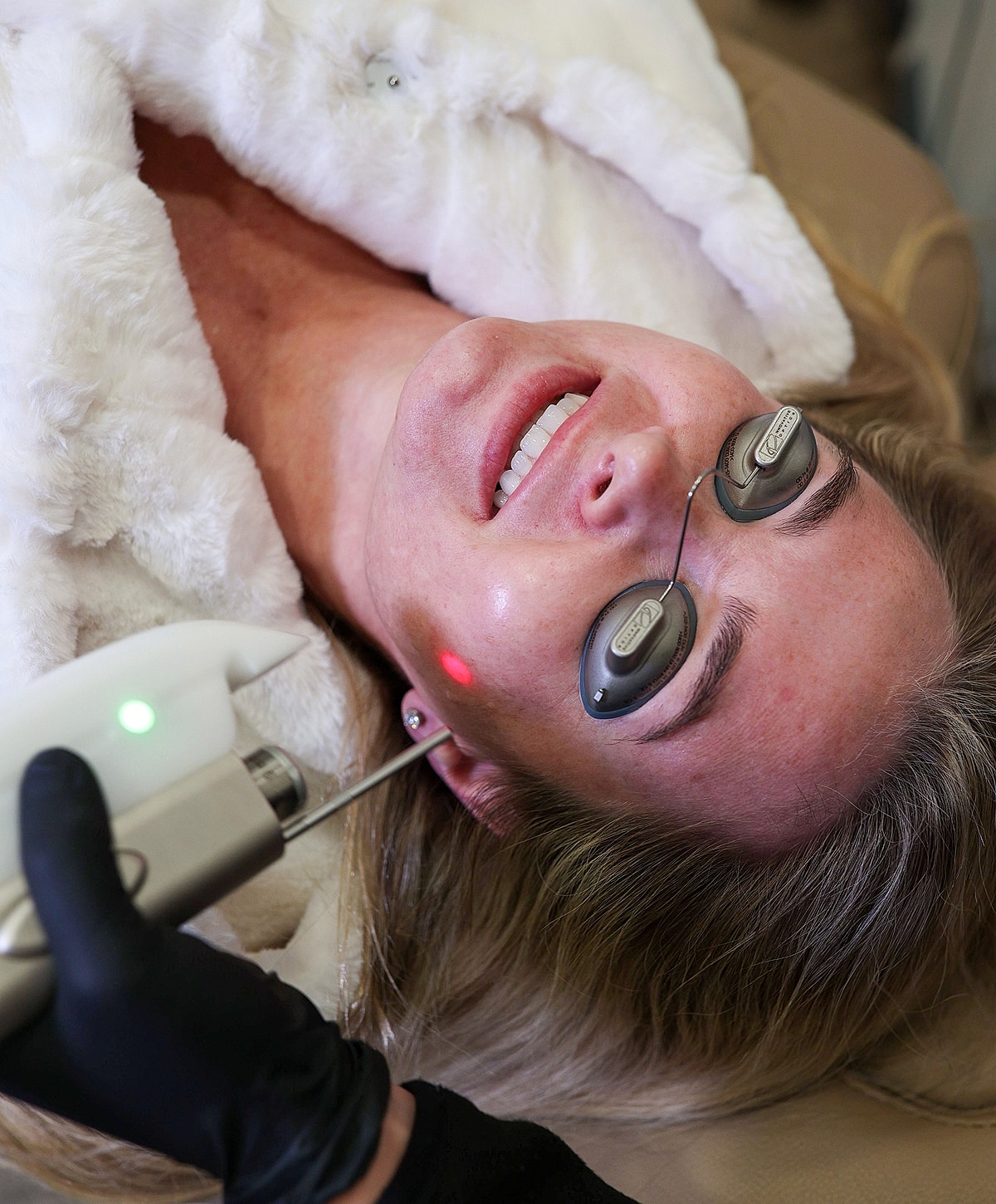 Woman receiving facial treatment with laser equipment.