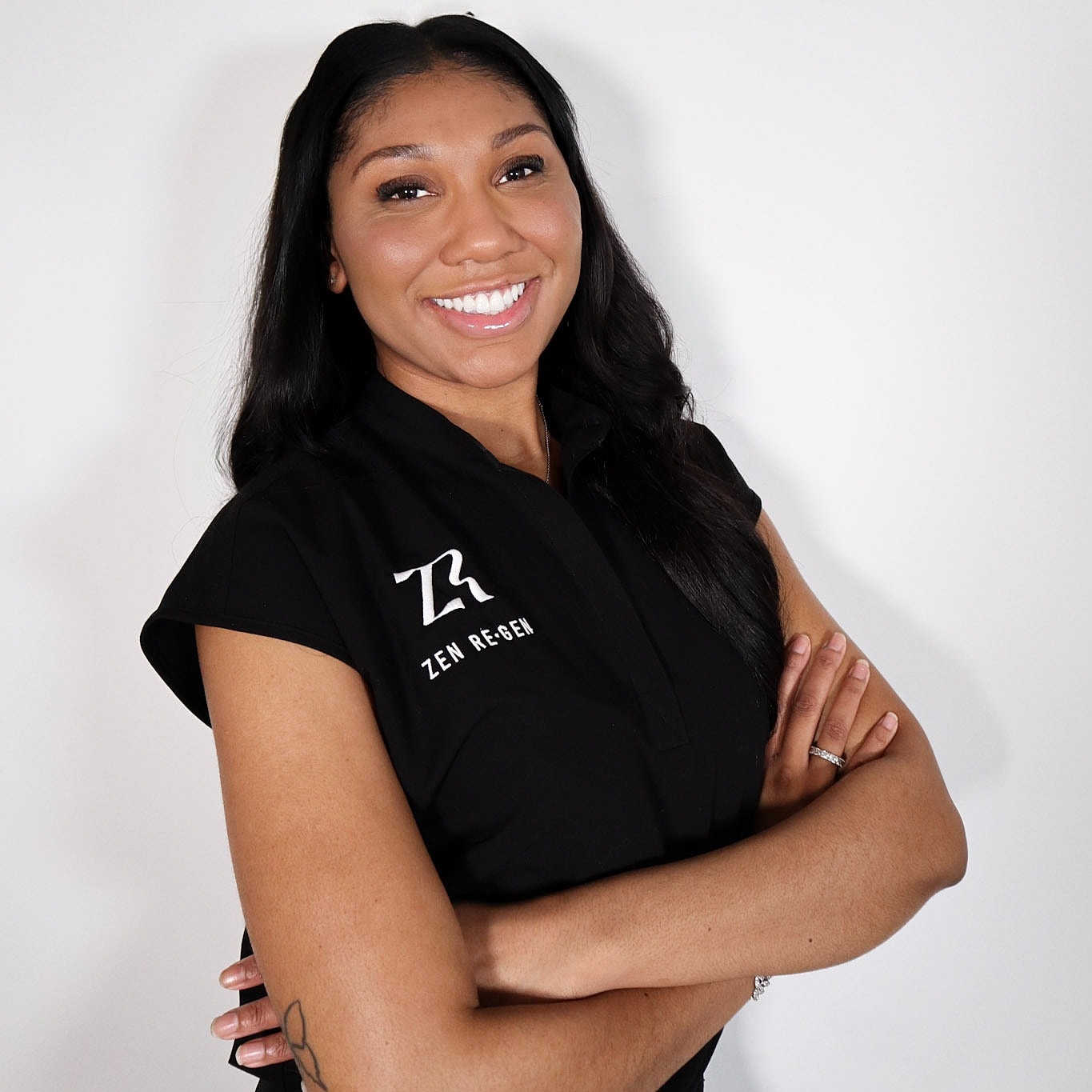 Smiling woman in branded shirt, arms crossed.