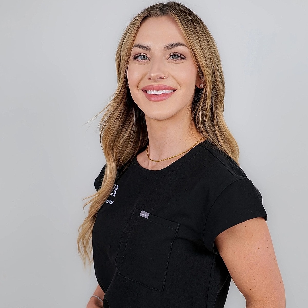 Smiling woman in professional attire against plain background.