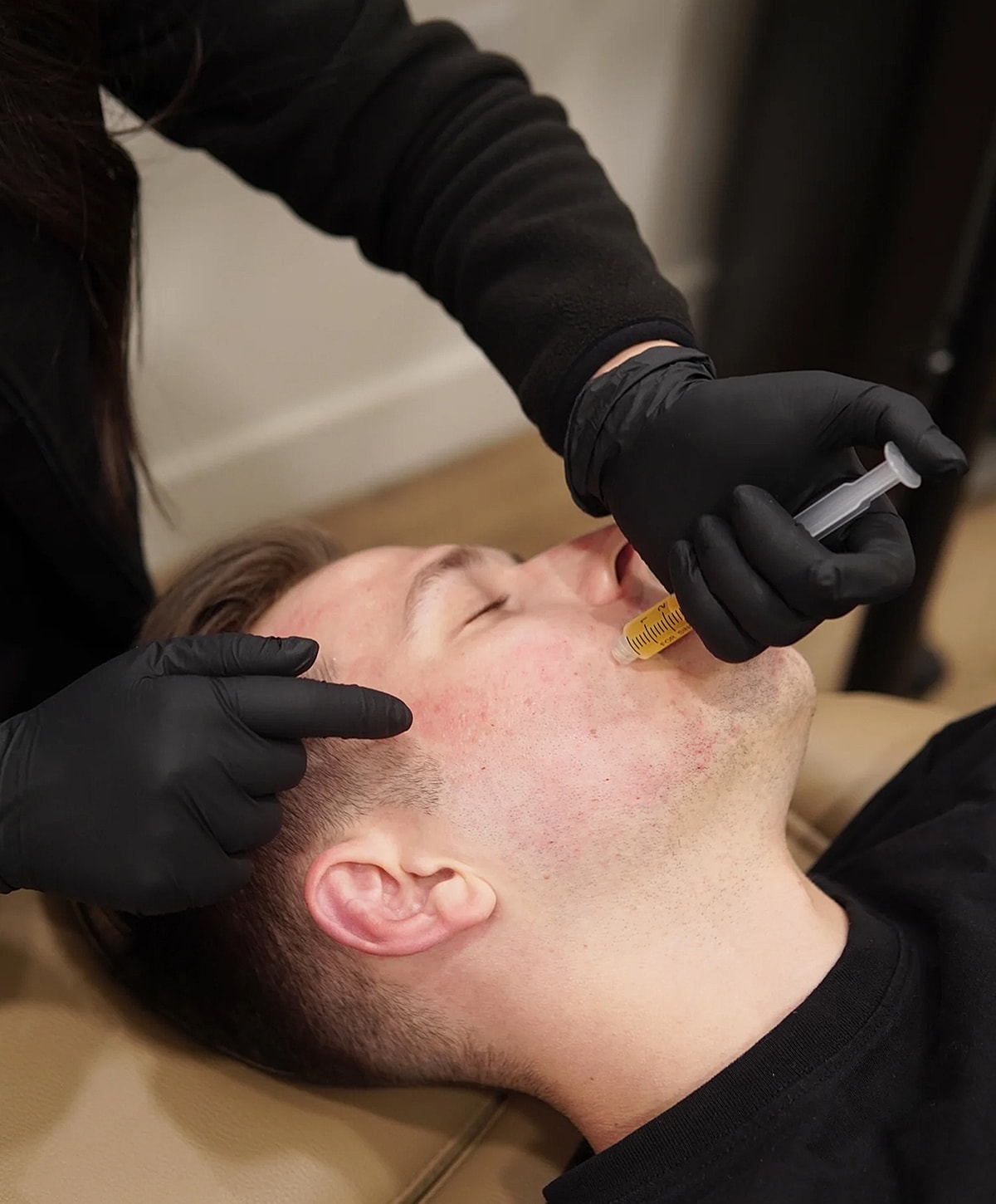 Person receiving facial treatment with syringe.