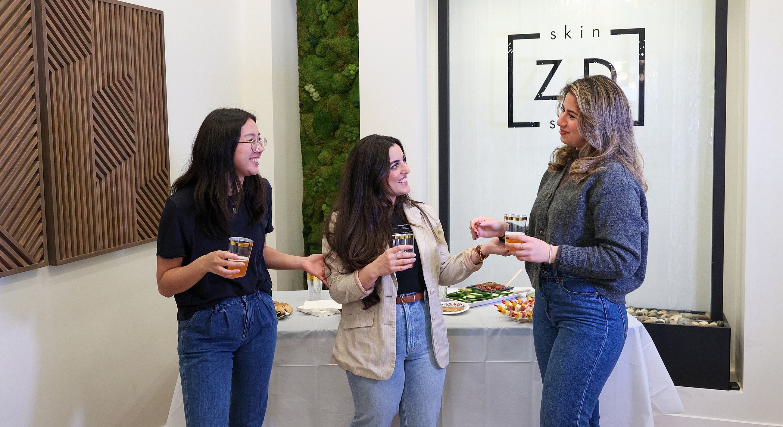 Three women enjoying drinks at a social gathering.
