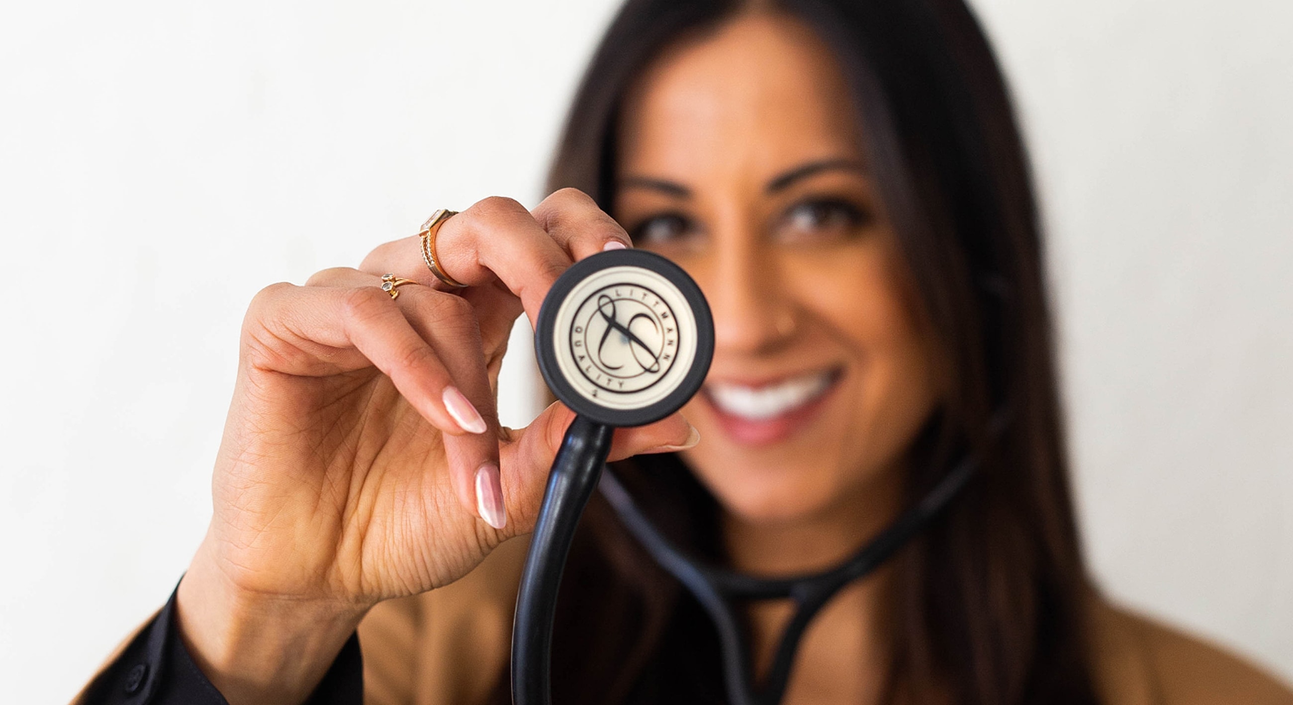 Smiling woman holding stethoscope with confidence.