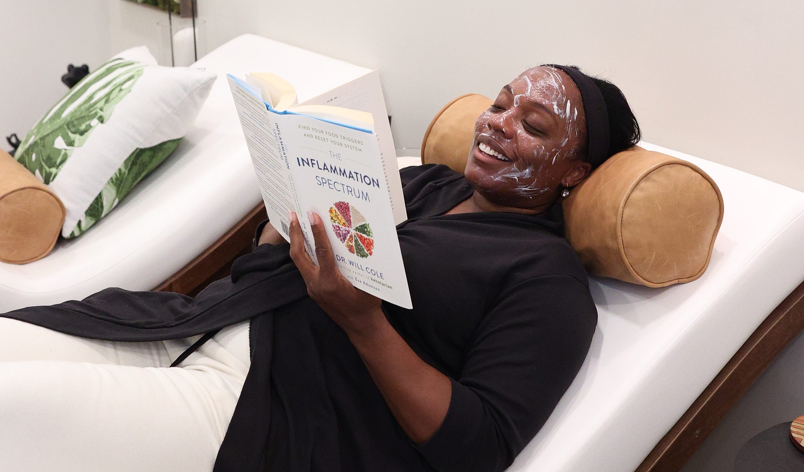 Woman relaxing with a face mask and book.