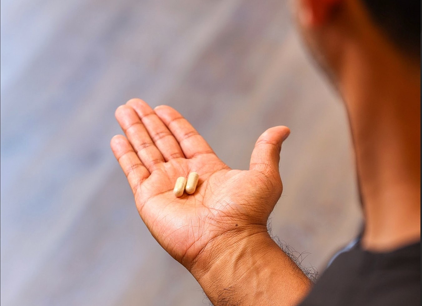 Hand holding two capsules on palm.